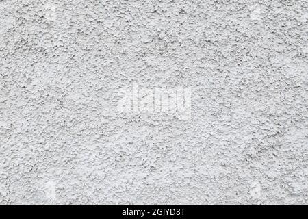 Close-up of a plastered and rough concrete or stone wall painted in white or light gray. High resolution full frame textured background. Copy space. Stock Photo