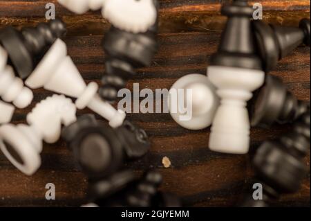 Black and white chess pieces scattered on a wooden table, close-up, selective focus Stock Photo