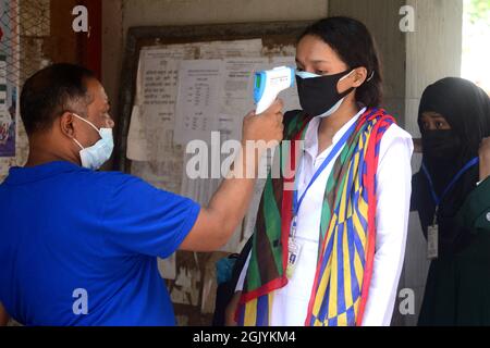 Dhaka, Bangladesh. September 12, 2021. An official checks the body temperature of a student upon her arrival at the Azimpur Government Girls School and College in Dhaka, Bangladesh, on September 12, 2021. After 543 days, primary, secondary and higher secondary schools across the country reopened maintaining Covid-19 guidelines and health protocols. Credit: Mamunur Rashid/Alamy Live News Stock Photo