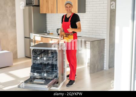 Young Repairman Service Worker Repairing Dishwasher Appliance In Kitchen Stock Photo