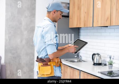 Male worker types on a tablet, kitchen renovation Stock Photo