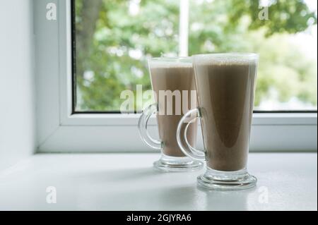 Couple of cocoa drinks on white windowsill. Hot chocolate. Stock Photo