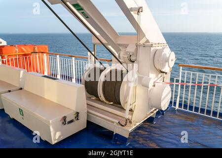 Steel reel of a crane on a deck of sailing ocean ship with sea horizon in the background. Stock Photo