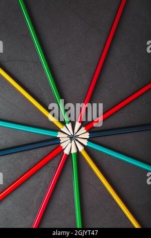 Wooden pencils of different colors in the shape of a star on a black background. Top view Stock Photo