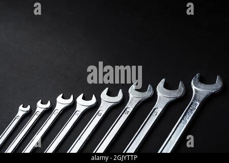 Tool wrenches in a row on a black background with free space. Top view Stock Photo