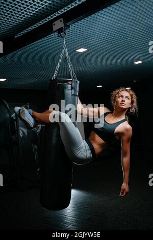 Female athlete on a punching bag to perform exercises on the press. Stock Photo