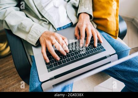Young man mobile developer, programmer writes program code on a laptop computer in home office. Stock Photo