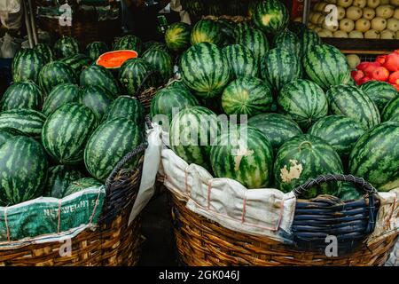 Many big green watermelons in basket and one cut.Sweet juicy summer refreshment,food background.Healthy eating full of vitamins. Lots of tasty ripe Stock Photo