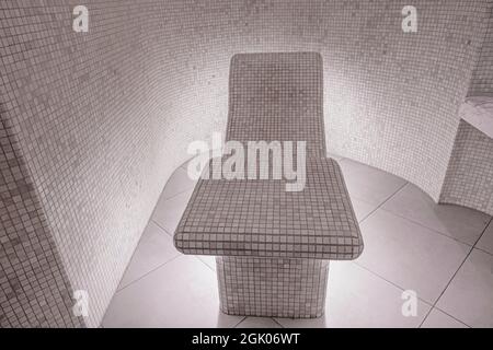 Hammam, traditional Turkish bath relaxation area with tiled seat and walls, illuminated from below; in luxurious spa Stock Photo