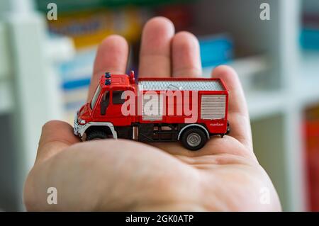 POZNAN, POLAND - Mar 25, 2018: A red model Siku brand toy fire truck on a open hand Stock Photo