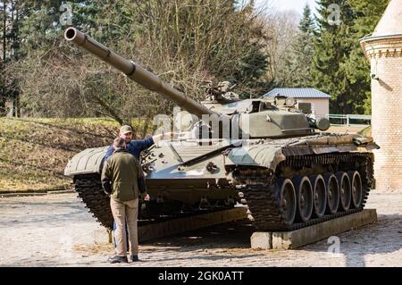 POZNAN, POLAND - Mar 25, 2018: Two men standing by an old exhibition tank of a museum in the Cytadela park Stock Photo