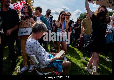 Amsterdam, Netherlands. 12th Sep, 2021. A woman sits while reading a book during the demonstration.The action group 'Woonprotest' organized a protest against the housing crisis in The Netherlands. Thousands of people gathered at the Westerpark in Amsterdam to demand to guarantee adequate and affordable housing for everyone, get a grip on escalating rent and house prices, stop racist and classical housing and demolition policy and stop wealthy investors. Credit: SOPA Images Limited/Alamy Live News Stock Photo