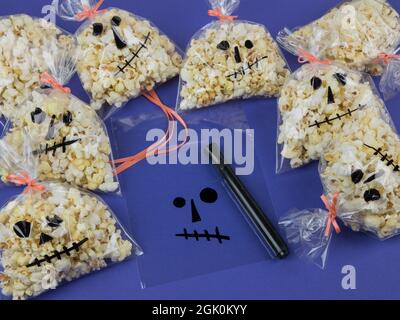 Preparing Halloween gifts. Woman's hands creating Halloween packaging for popcorn. Presents in the form of skull Stock Photo