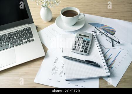 Finance accounting on an office desk with papers, laptop computer, calculator and a coffee cup, business concept, selected focus, narrow depth of fiel Stock Photo