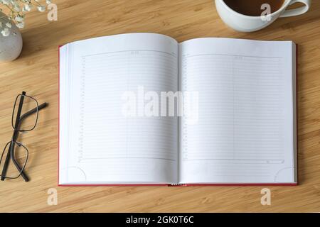 Flat lay mock-up of a blank open diary or appointment calendar on a wooden desk with coffee and glasses, time management concept, copy space, selected Stock Photo