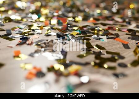 Glow golden confetti on floor close up. Celebration decoration. Sparkle of gold metallic party decor Stock Photo
