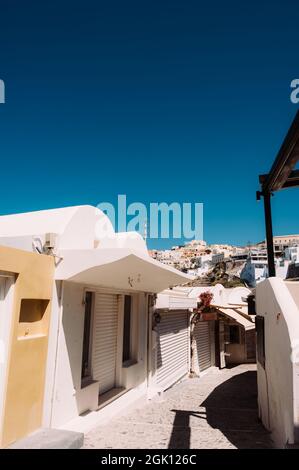 Empty narrow street in Thira, Santorini island. Closed shops during coronavirus lockdown. White greek architecture/