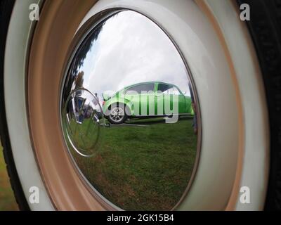 Reflection of a restored and customised VW Beetle in the hub cap of another Beetle Stock Photo