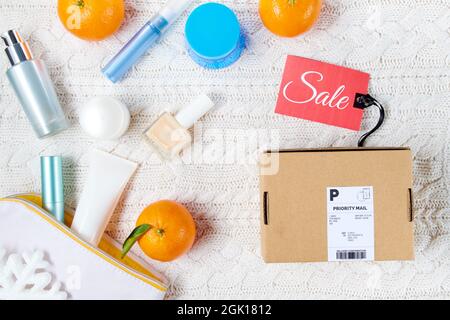 winter flat lay with parcel, cosmetics, snowflake, sale tag and mandarins on white knitted background. Stock Photo