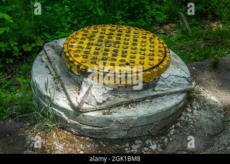 Yellow sewer cast-iron manhole cover on concrete base. Sewage drainage system Stock Photo