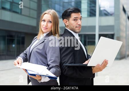 Two office workers are posing with laptop and folder Stock Photo