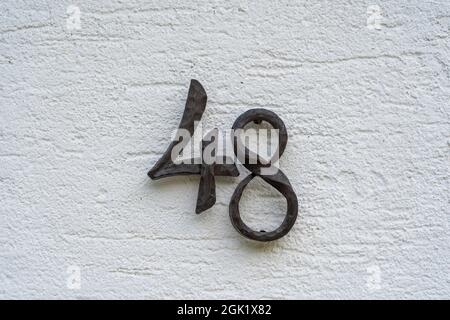 Metal house number 48 on a white stucco wall background, close up Stock Photo