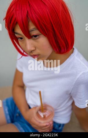 Red Blood Cell Cosplay Actress Seated Drinking a Smoothie | Asian Teenage Girl in Red Wig