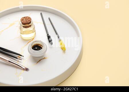 Tray with henna and tools for eyebrows correction on color background Stock Photo