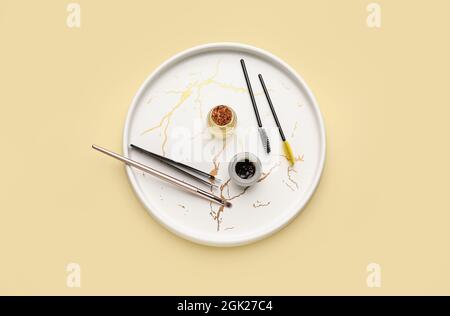 Tray with henna and tools for eyebrows correction on color background Stock Photo
