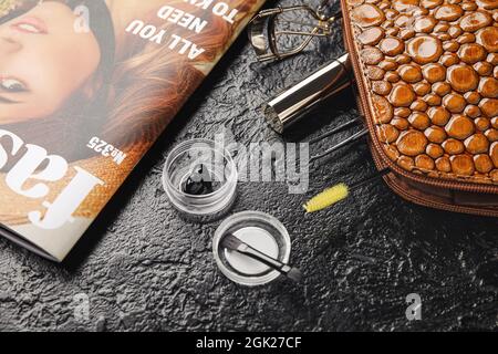 Cosmetic bag, henna, tools for eyebrows and eyelashes correction on dark background, closeup Stock Photo