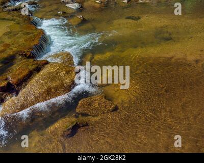 Clear water in a stream, near rocks and waterfalls with copy space. Natural shallow stream water background. Stock Photo