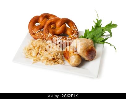 Plate with tasty Bavarian sausages, sauerkraut and pretzels on white background. Oktoberfest celebration Stock Photo