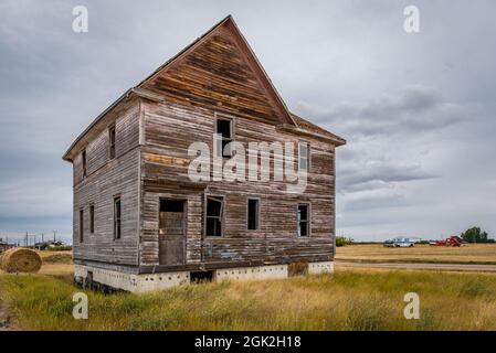 An old, abandoned home and classic pick-up trucks in the ghost town of Robsart, Saskatchewan Stock Photo