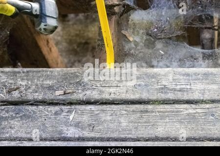 yellow crowbar with a metal mallet prying up boards on a porch Stock Photo