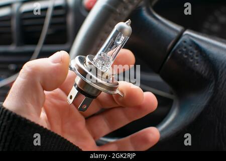 close up view of the burnt out spiral of a nichrome filament of a car lamp in the driver hand, located inside the car Stock Photo