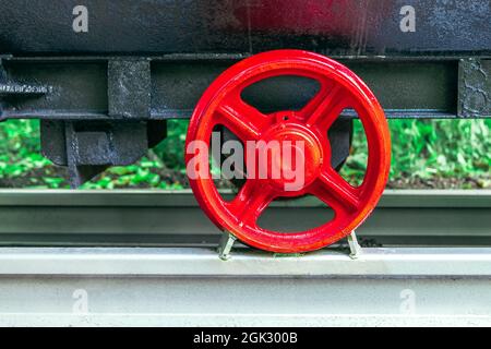 the undercarriage of a traditional mine cart. a restored, old mine car on a fragment of a railway track. the red steel wheels and the black plate of t Stock Photo