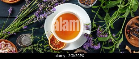 Tea panorama with herbs, flowers and fruit, shot from the top on a dark rustic wooden background Stock Photo