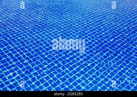 Swimming pool surface texture close up top view, blue water background, caustics ripple, swimming pool tiled bottom backdrop, sea beach summer holiday Stock Photo