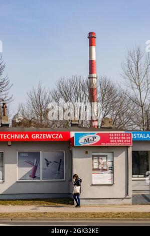 POZNAN, POLAND - Mar 25, 2018: A woman standing in front of an M&P sanitary store with a chimney in the background Stock Photo