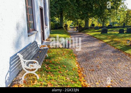 Empty park bench by a church wall Stock Photo