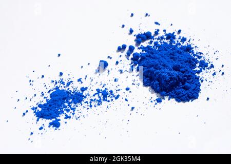 Large and small portion of ultramarine, cobalt or indigo blue pigment on white. The pigment was mixed with linseed oil to make oli paint Stock Photo