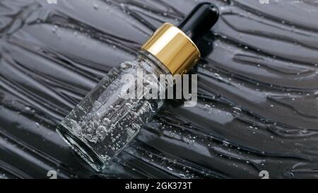 Serum on Liquid gel or hyaluronic Collagen serum in dropper on black color water wave texture background. Skincare cosmetic product pipette bottle Stock Photo