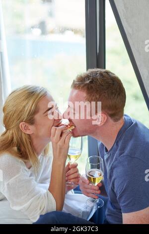 Young couple in love sharing last piece of pizza when having romantic dinner at home Stock Photo