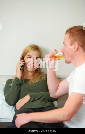 Cheerful young woman making phone call to order pizza for romantic dinner at home Stock Photo