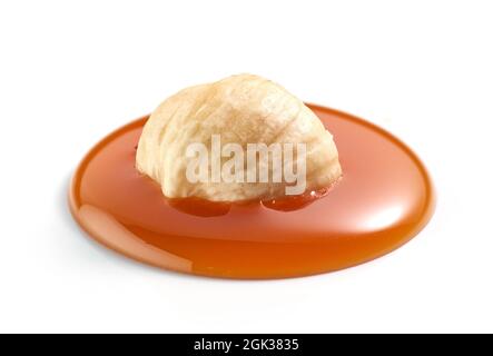 hazelnut in melted caramel drop isolatedd on white background Stock Photo