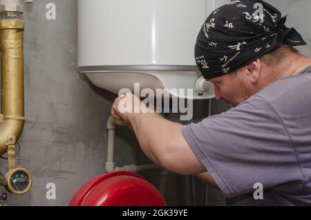 A water heater specialist works in the boiler room. An adult mal Stock Photo