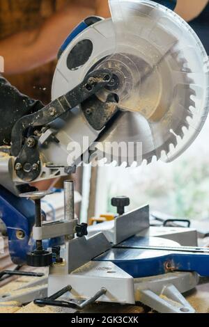 Professional miter saw standing on stack of boards with trim planks