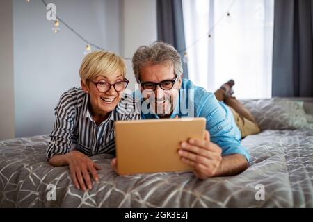 Lovely smiling mature couple having fun while using tablet at home Stock Photo