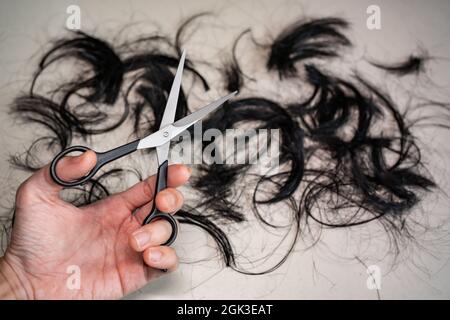 Professional hair cutting scissors in left hand with hair on the floor Stock Photo