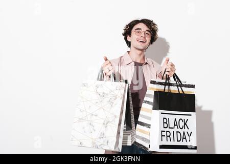 Portrait of happy young man holding shopping bags and smiling at camera isolated on white background Stock Photo